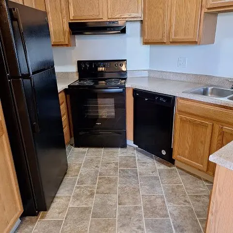 Kitchen with wooden cabinets and black appliances.