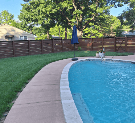 Backyard pool with umbrella and fence.