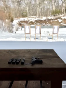 Pistol and magazines on table, snowy shooting range.