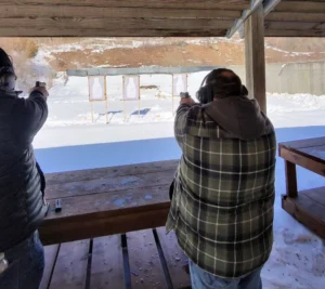 Two people shooting at outdoor targets.